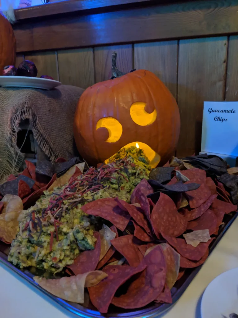 Geschnitzter Kürbis über einer Platte mit Nachos und Guacamole