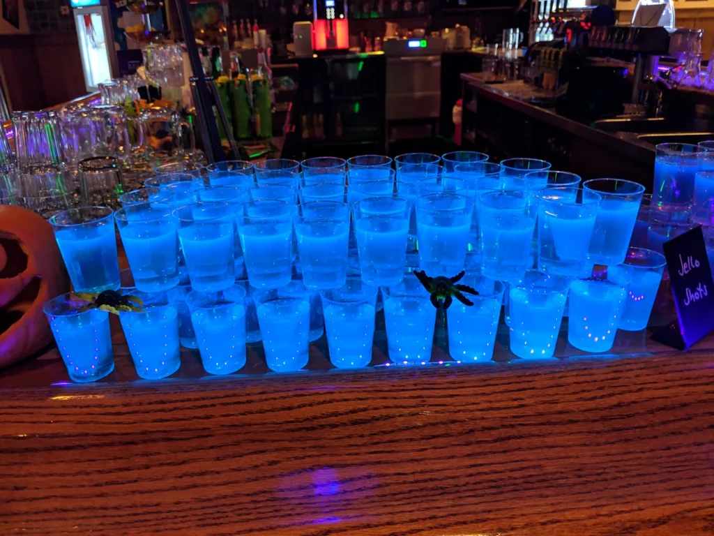 Leuchtend blaue Halloween-Shots in Reihen auf dem Bartresen